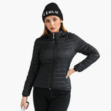 Femme portant une veste matelassée noire avec capuche et bonnet, posant avec la main sur la hanche