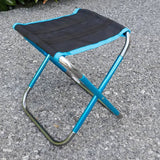 Mini chaise de camping pliable bleu et gris sur sol extérieur