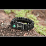 Bracelet de survie noir en paracorde avec boussole sur fond rocheux