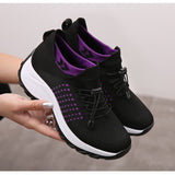 Chaussures de marche noires et violettes pour femmes, présentation tenue dans la main