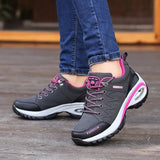 Chaussures de marche pour femmes en noir et rose, avec semelles épaisses et lacets, portées en extérieur