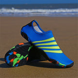 Chaussures aquatiques bleues avec rayures jaunes, posées sur le sable de la plage
