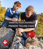 Couple utilisant une trousse de premiers secours en extérieur, essentiel pour les randonnées et les urgences