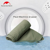 Doublure de sac de couchage verte pouvant être lavée en machine, présentée devant une machine à laver