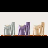 Ensemble de sous-vêtements thermiques pour femme en beige, violet et gris, exposés sur une table