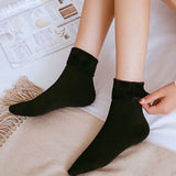 Femme allongée portant des chaussettes noires en peluche, chaussettes de maison