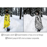Femme portant une couverture de survie dorée et argentée en pleine neige