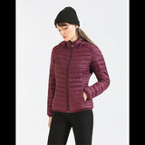 Femme portant une veste matelassée rouge avec capuche, mains dans les poches