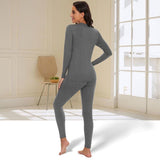 Femme portant un ensemble thermique gris, vue de dos, intérieur chaleureux