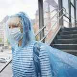 Femme portant un poncho imperméable bleu avec masque à l'extérieur