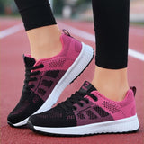 Gros plan sur chaussures de sport noires et roses, portées sur une piste d’athlétisme