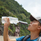 Homme utilisant un filtre à eau portable, buvant de l'eau propre en randonnée