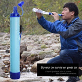 Homme utilisant un purificateur d'eau portable pour boire directement d'une rivière