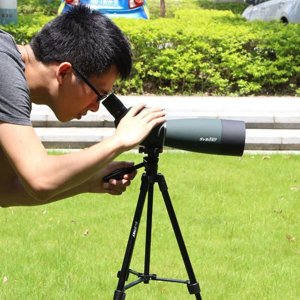 Homme utilisant un télescope sur trépied pour observer à distance