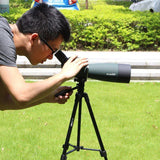 Homme utilisant un télescope sur trépied pour observer à distance