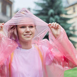 Jeune femme souriante portant un poncho imperméable rose en extérieur