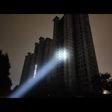 Lampe de poche étanche projetant un faisceau lumineux sur des bâtiments de nuit