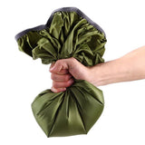 Main serrant une housse de sac à dos imperméable verte, montrant sa flexibilité et sa durabilité