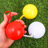 Main tenant trois ponchos imperméables portables en boule rouge, blanche et jaune