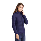 Femme portant une veste matelassée bleue avec capuche, posant de manière décontractée
