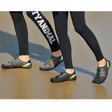 Personnes marchant sur la plage avec des chaussures de natation grises et noires, idéales pour le bord de mer
