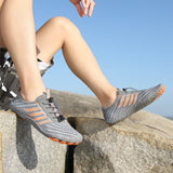 Personne portant des chaussures aquatiques gris et orange sur un rocher, idéales pour le plein air