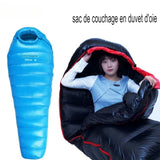Sac de couchage en duvet d'oie bleu et noir, femme se préparant pour une nuit confortable