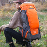 Sac à dos de camping 65 L orange et gris sur femme assise, idéal pour randonnée et trekking
