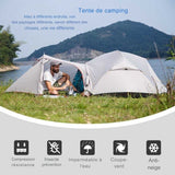 Tente de camping montée au bord d'un lac avec une personne assise à l'entrée, idéale pour aventure en plein air