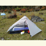 Tente de randonnée argentée montée sur un terrain herbeux avec équipement de camping à l'intérieur