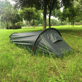 Tente de camping noire pour une personne, installée dans un cadre forestier
