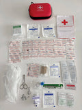 Trousse de premiers secours ouverte avec contenu, incluant des bandages, des gants et un livret de premiers secours