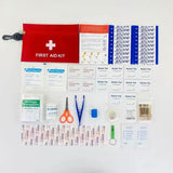 Trousse de premiers secours rouge ouverte avec contenu étalé, comprenant des pansements, des ciseaux, et des tampons alcoolisés