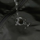 Veste imperméable noire avec traitement hydrophobe, montrant l'eau qui perle sur le tissu